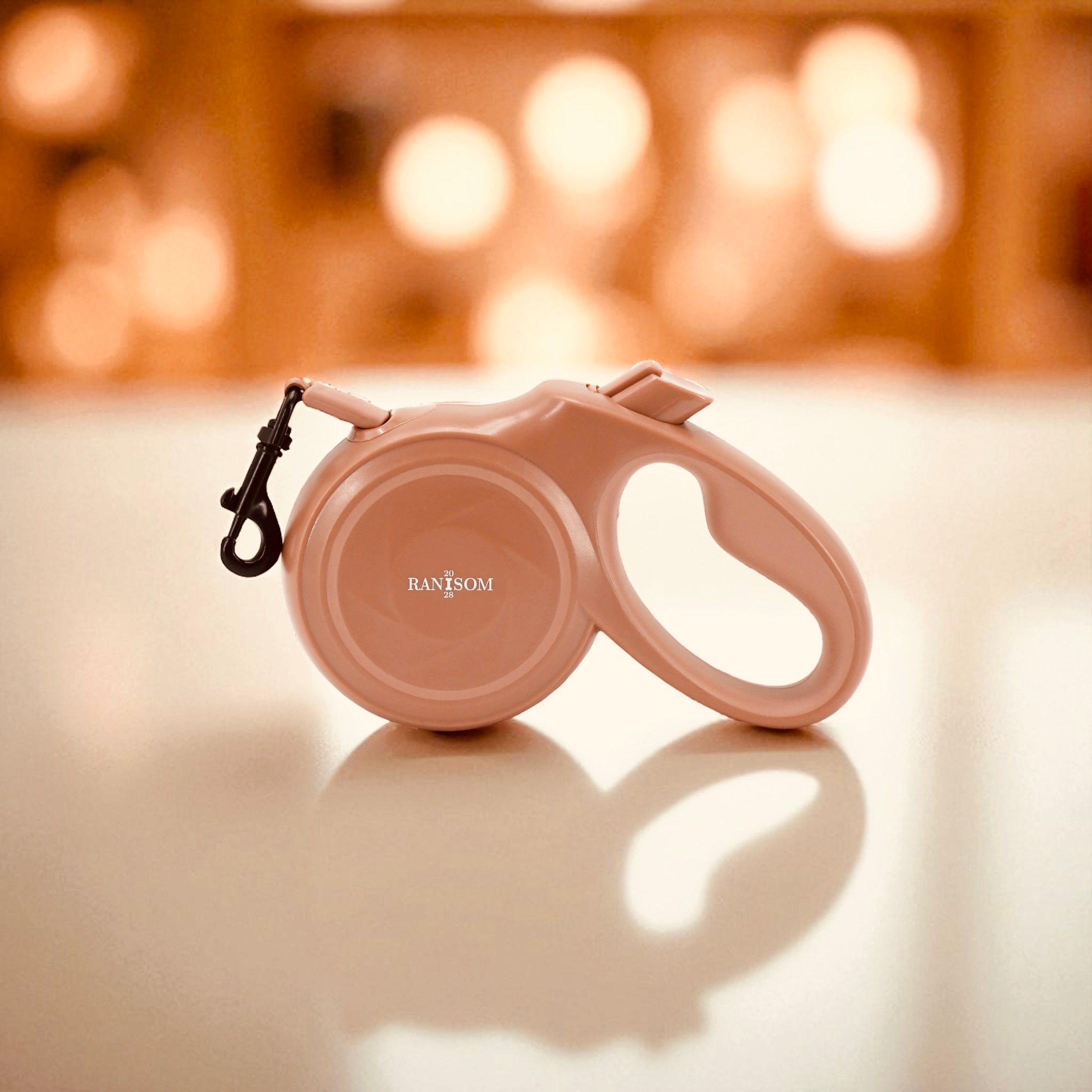 Luxury neutral brown retractable dog leash by RANSOM 20:28 in front of a bokeh background